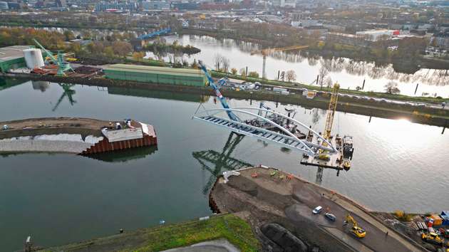 Die Stabbogenbrücke wurde mit Hilfe von zwei schwimmenden Schwerlastkränen  eingehoben. Der „Matador“ und der „Hebo-Lift 8“ wurden aus Rotterdam geholt: Der eine kann bis zu 400 Tonnen tragen, der andere 300 Tonnen.